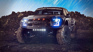 Mickey Thompson Ford Raptor Off-Road Truck on Rocky Terrain at Night HD wallpaper