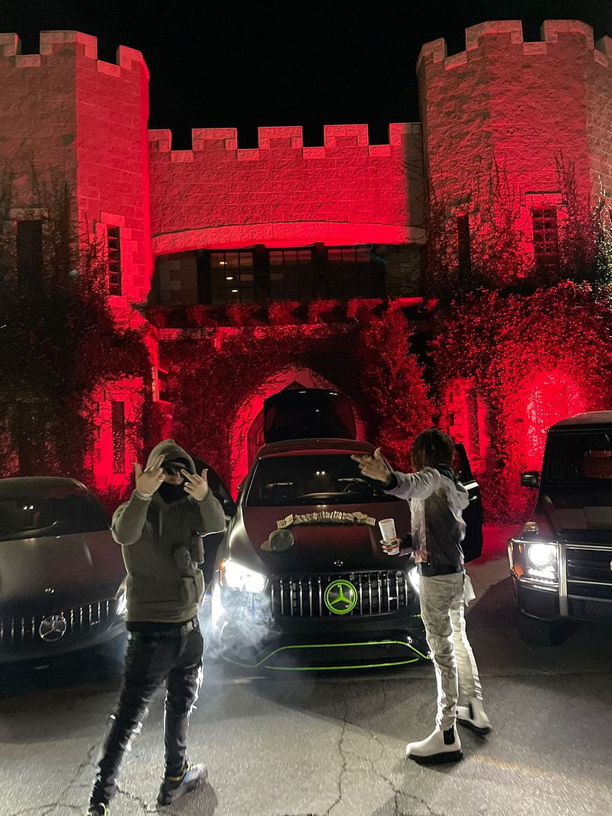 YEAT posing with a customized Mercedes AMG in front of a red-lit castle at night HD phone wallpaper