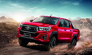 Red Toyota Hilux Revo Rocco Pickup Truck Driving on Dusty Off-Road Terrain HD wallpaper