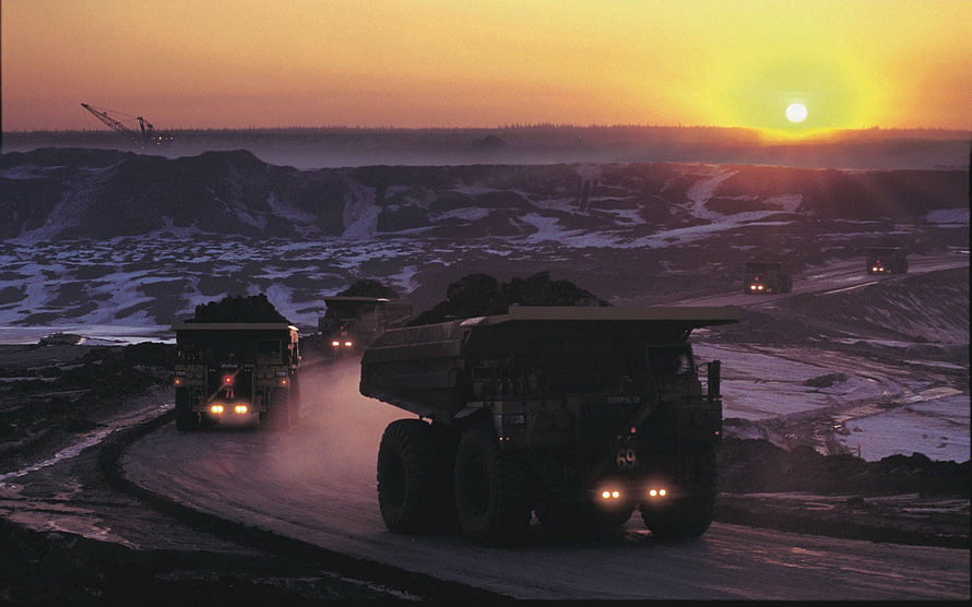 Heavy Haul Trucks Transporting Ore in an Open Pit Mine at Sunset HD wallpaper