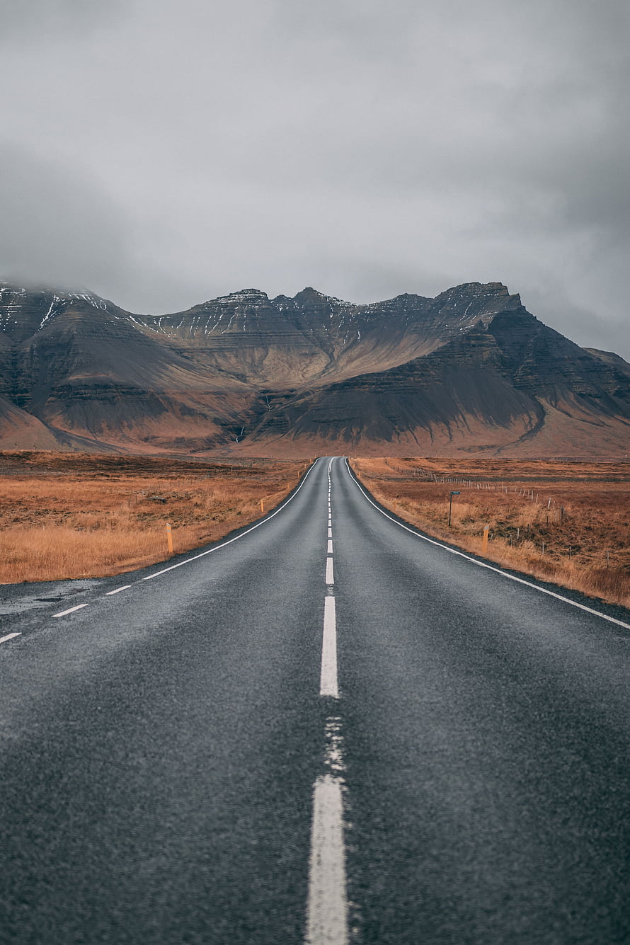 Empty Highway Stretching Toward Snow-Capped Icelandic Mountains Under Overcast Sky HD phone wallpaper
