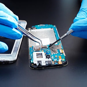 Close-up of smartphone internal repair with precision tools and blue nitrile gloves on a dark workbench HD phone wallpaper
