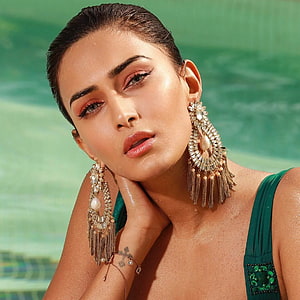 Erica Fernandes in Emerald Green Attire with Ornate Gold Jhumka Earrings by a Pool HD phone wallpaper