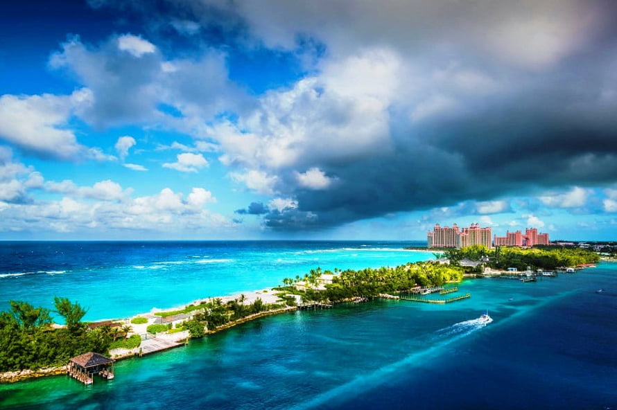 Aerial View of Tropical Island Resort with Turquoise Waters and Dramatic Clouds HD wallpaper