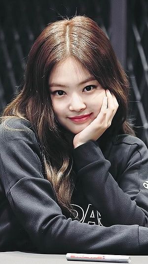Jennie Kim from Blackpink in a black hoodie with a gentle smile and hand on cheek HD phone wallpaper