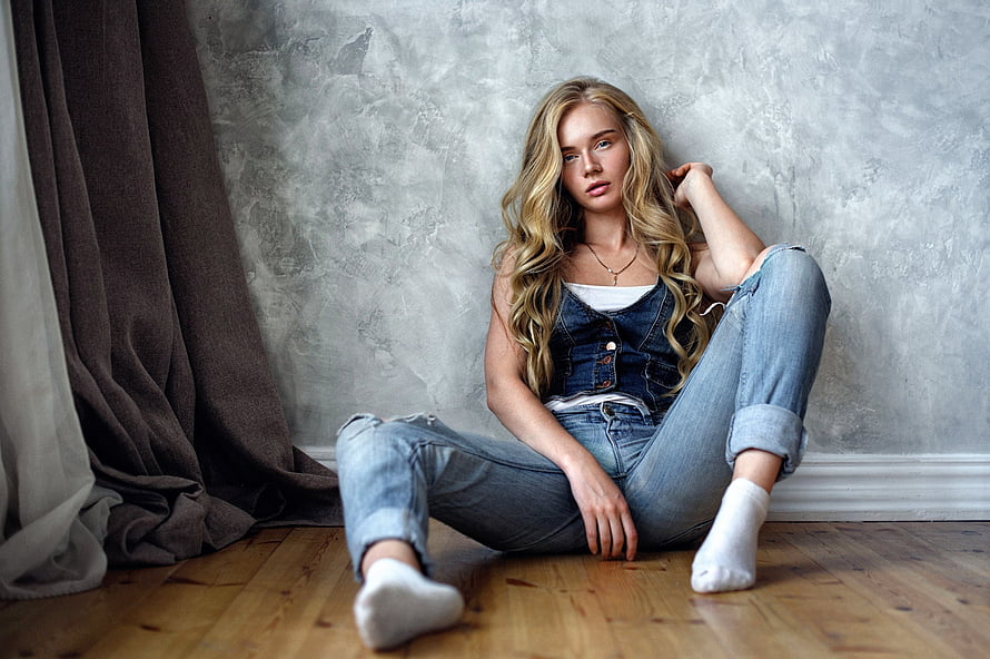 Blonde Woman in Denim Overalls Sitting on Wooden Floor Against Textured Wall HD wallpaper