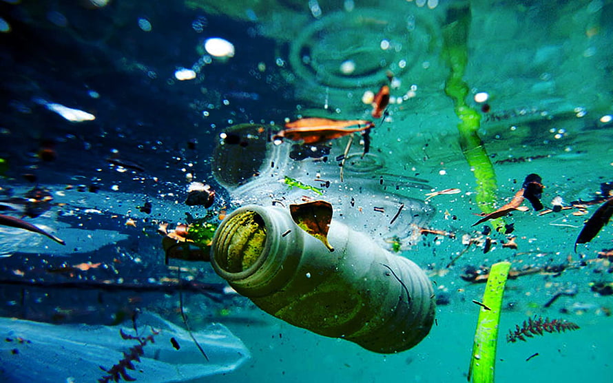 Plastic Bottle Floating in Turquoise Water with Debris and Bubbles HD wallpaper