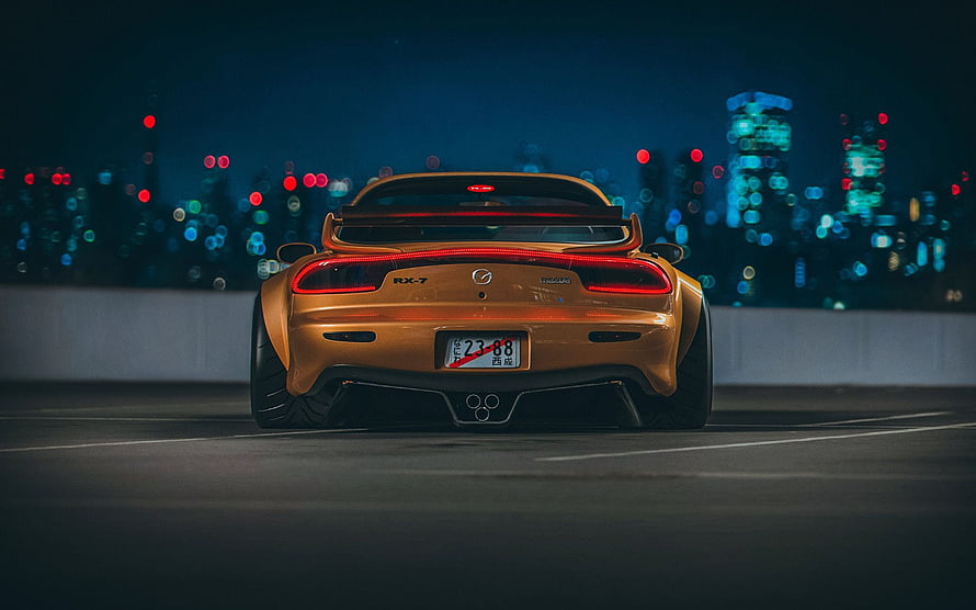 Rear View of a Gold Mazda RX-7 on a Night Highway with City Bokeh Lights HD wallpaper