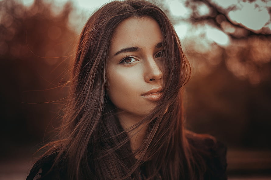 Cinematic Portrait of a Young Woman with Windblown Hair and Warm Autumn Tones HD wallpaper