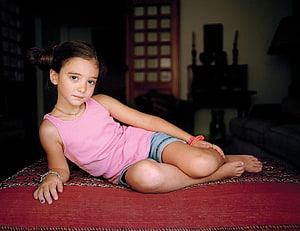 Young Girl in Pink Tank Top Sitting on Red Rug in Cozy Living Room HD wallpaper