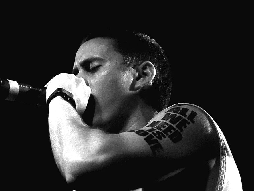 Canserbero performing live on stage in dramatic black and white portrait HD wallpaper