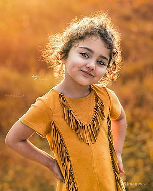 Anahita Hassanzadeh in a mustard suede fringe dress with curly hair against a warm autumn background HD phone wallpaper