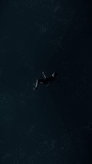 Silhouette of a Falling Astronaut Drifting Through the Vast Darkness of Deep Space HD phone wallpaper