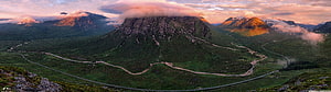 Panoramic View of Glencoe Valley with Winding Roads and Dramatic Mountain Peaks at Sunset HD wallpaper
