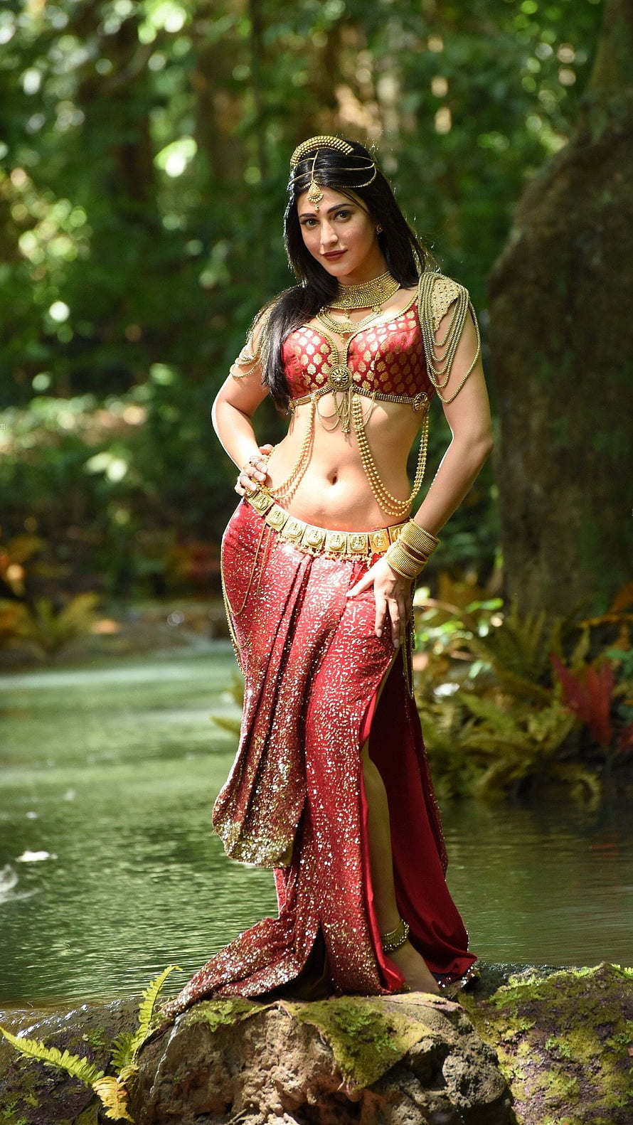 Shruthi Hassan in Traditional Red Ethnic Wear with Gold Jewelry in a Lush Forest Setting HD phone wallpaper