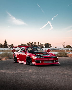 Red Modified JDM Coupe with Large Rear Wing Parked on Asphalt at Sunset HD phone wallpaper