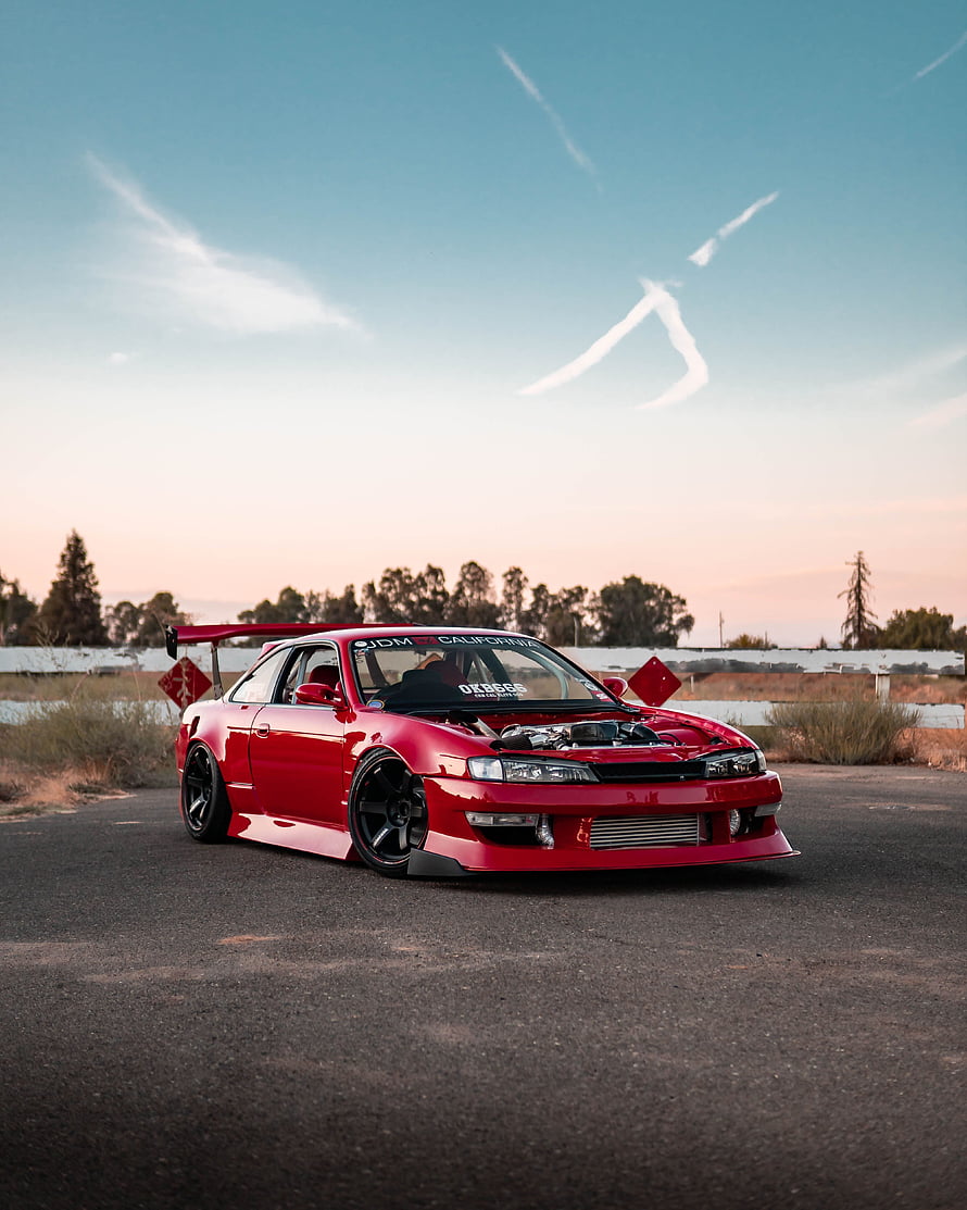 Red Modified JDM Coupe with Large Rear Wing Parked on Asphalt at Sunset HD phone wallpaper