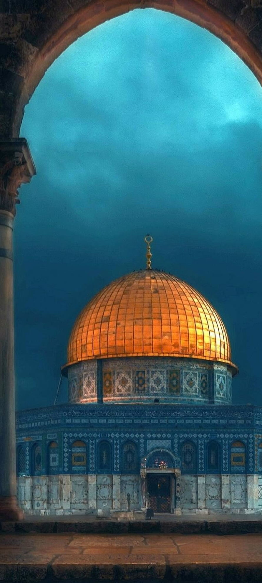 Dome of the Rock in Jerusalem framed by a stone archway against a dramatic teal sky HD phone wallpaper