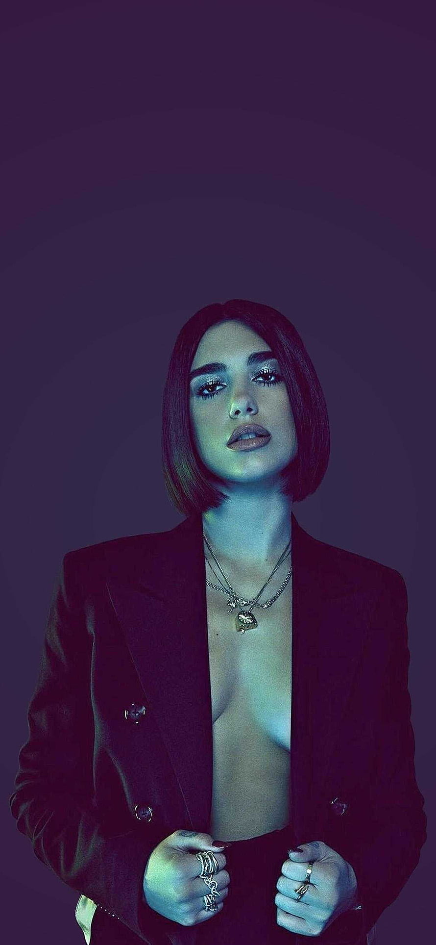 Dua Lipa in a dark blazer with layered necklaces and rings under moody purple lighting HD phone wallpaper