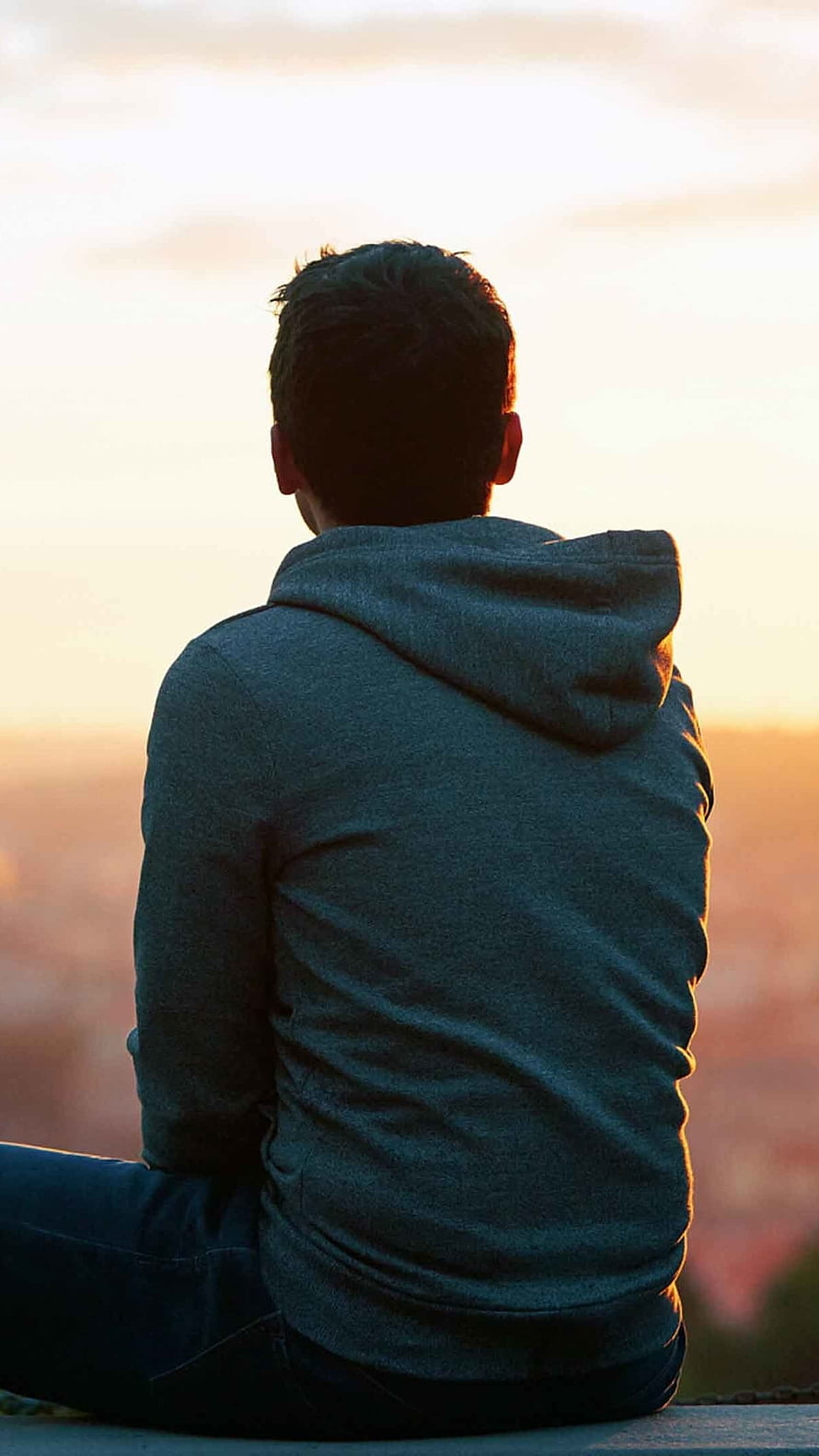 Man in Grey Hoodie Sitting Alone Watching Sunset Over City HD phone wallpaper