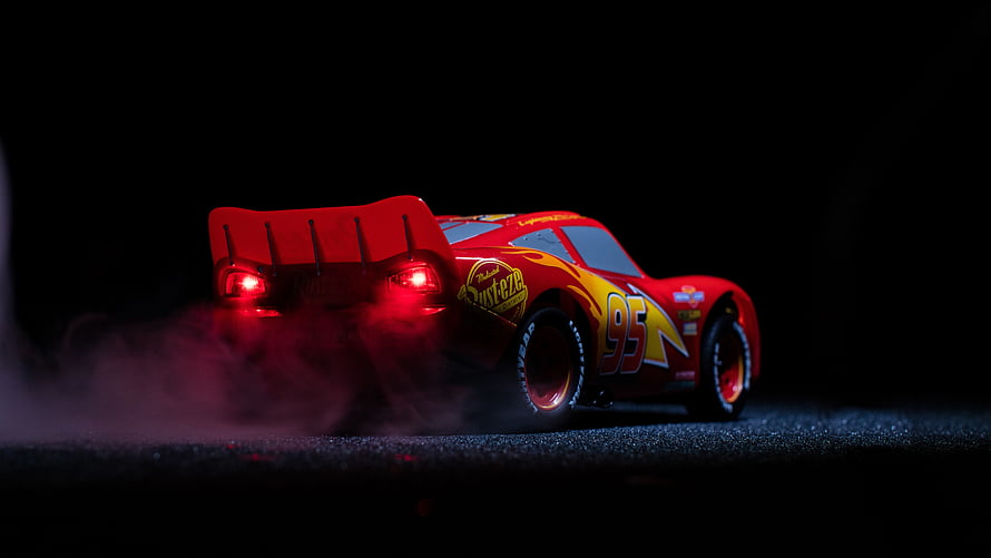 Lightning McQueen from Cars 3 drifting with smoke and glowing taillights on a dark track HD wallpaper