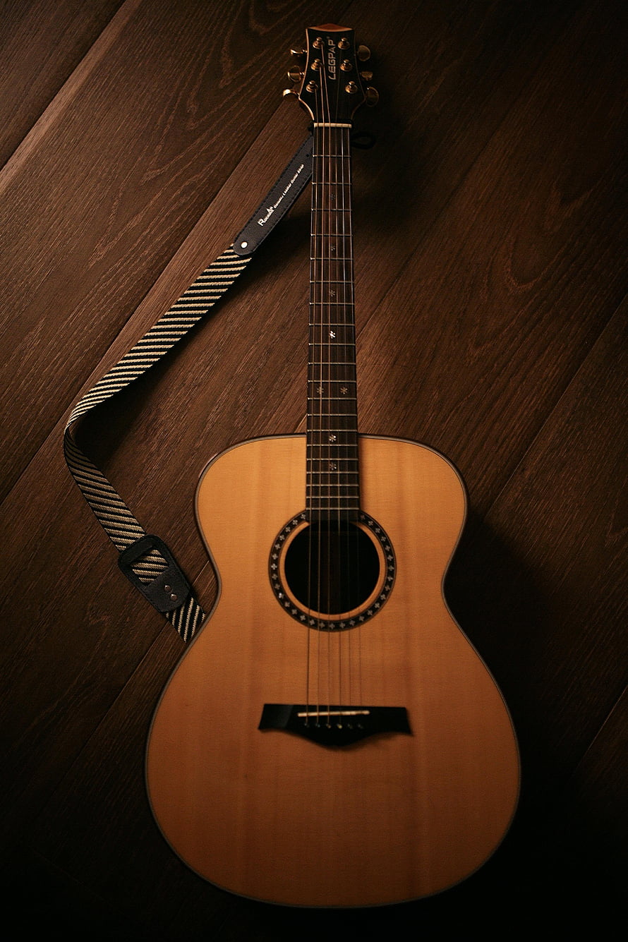 Acoustic Guitar with Striped Strap on Dark Wood Floor HD phone wallpaper