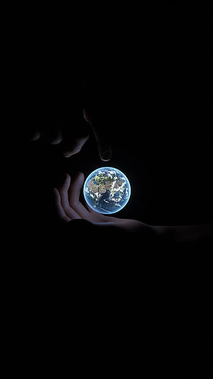 Human Hands Cradling a Glowing Earth Globe Against a Dark Void Background, Apple 14 Pro, 14 Pro Max HD phone wallpaper