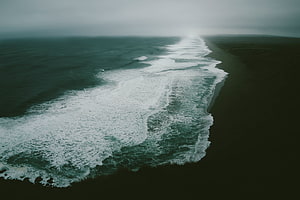 Aerial View of Dark Ocean Waves Crashing on a Misty Shoreline HD wallpaper
