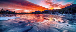 Frozen Lake at Sunset with Vibrant Orange Sky and Mountain Reflections HD wallpaper