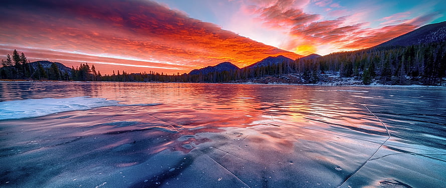 Frozen Lake at Sunset with Vibrant Orange Sky and Mountain Reflections HD wallpaper