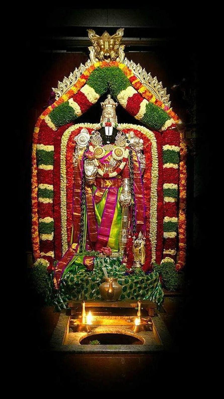 Tirupati Balaji deity adorned with vibrant flower garlands and traditional temple ornaments HD phone wallpaper