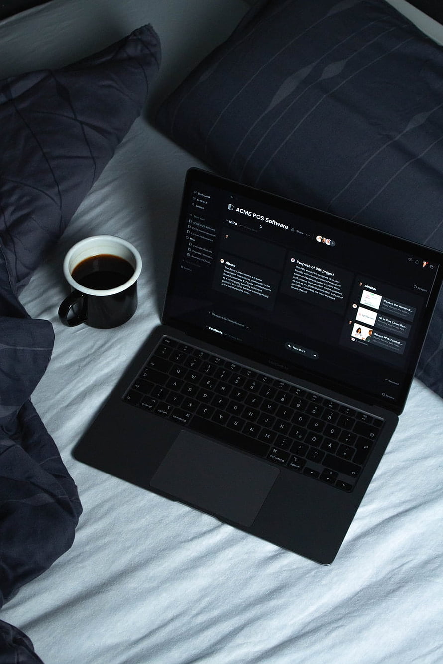 Black laptop and coffee mug on a bed with dark bedding HD phone wallpaper
