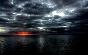 Dramatic Dark Stormy Sky Over Ocean at Sunset with Fiery Horizon HD wallpaper