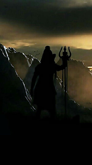 Silhouette of Lord Shiva Holding Trishula on a Mountain Ridge at Dusk HD phone wallpaper