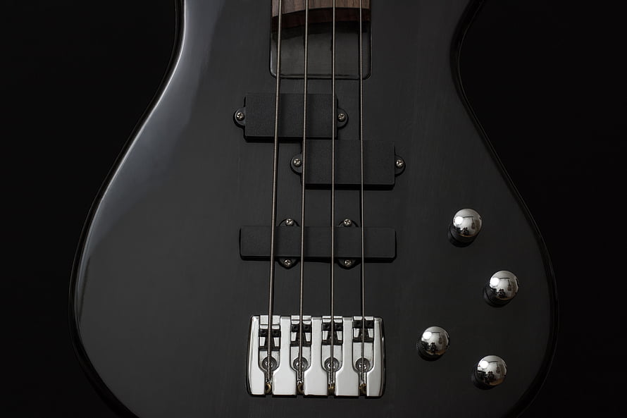 Close-up of a black electric bass guitar body with chrome hardware and strings HD wallpaper