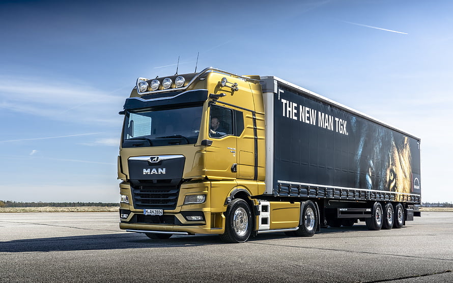 Yellow MAN TGX Heavy-Duty Truck with Cargo Trailer on Open Tarmac HD wallpaper