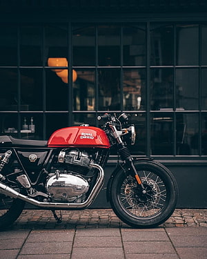 Red Royal Enfield Classic 350 motorcycle parked on cobblestone street in front of dark storefront HD phone wallpaper