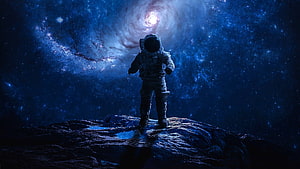 Lone Astronaut Standing on Rocky Terrain Facing a Distant Nebula in Deep Space HD wallpaper