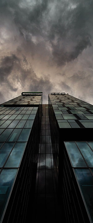 Dramatic Low-Angle View of Modern Glass Skyscrapers Under Stormy Clouds HD phone wallpaper