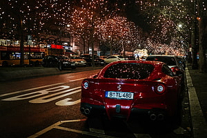 Red Ferrari California Rear View Parked on a City Street at Night with Festive Tree Lights HD wallpaper