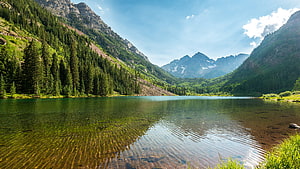 Serene Alpine Lake Surrounded by Lush Forested Mountains and Clear Blue Sky HD wallpaper