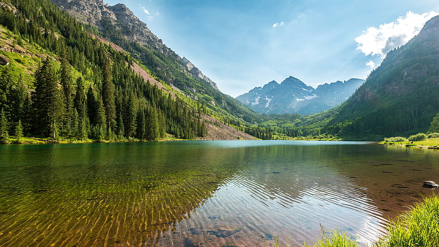 Serene Alpine Lake Surrounded by Lush Forested Mountains and Clear Blue Sky HD wallpaper