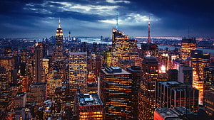 New York City Manhattan Skyline at Dusk with Illuminated Skyscrapers and Dramatic Clouds HD wallpaper