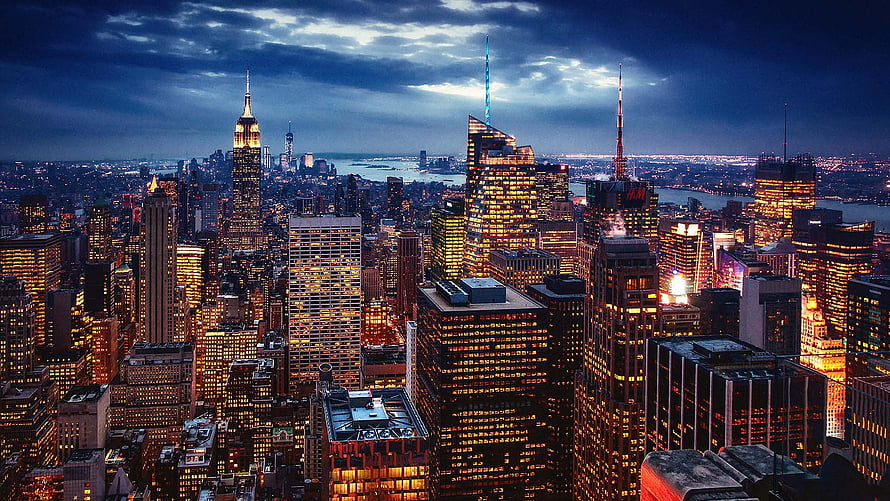 New York City Manhattan Skyline at Dusk with Illuminated Skyscrapers and Dramatic Clouds HD wallpaper
