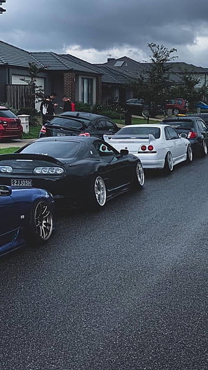 JDM Supercars Parked on a Residential Street Under a Stormy Sky HD phone wallpaper
