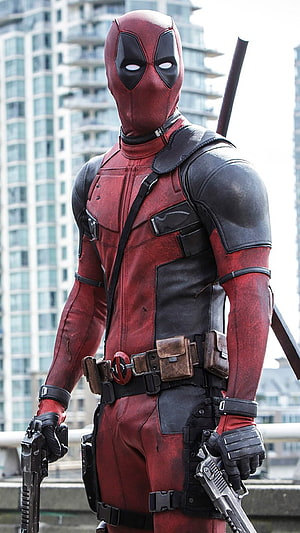 Deadpool in red and black tactical suit holding dual pistols on a city rooftop HD phone wallpaper