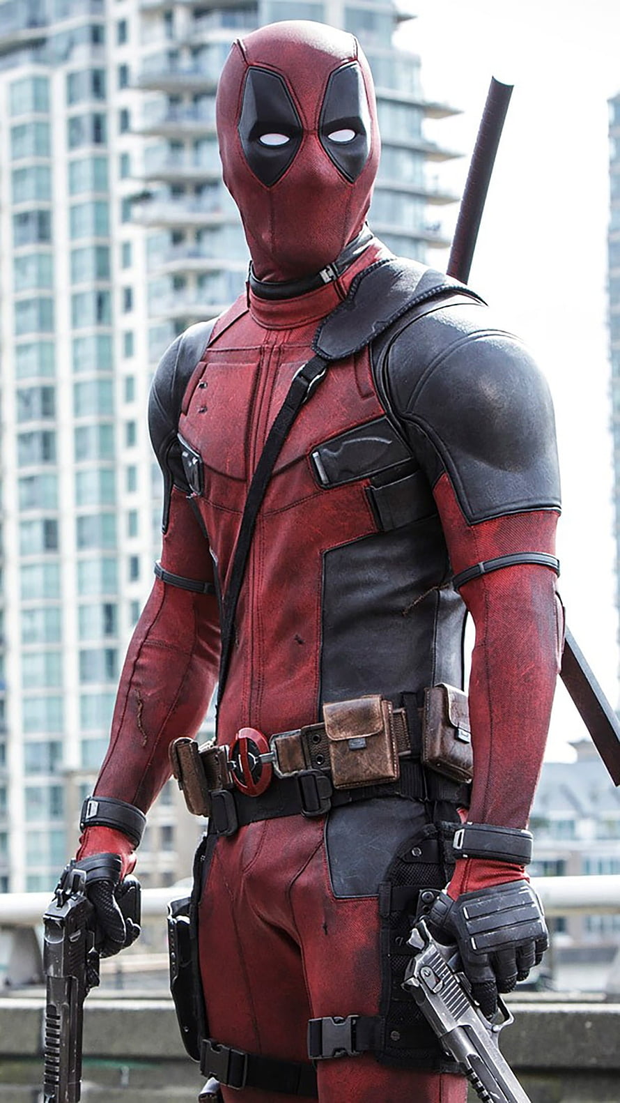 Deadpool in red and black tactical suit holding dual pistols on a city rooftop HD phone wallpaper