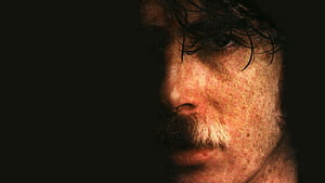 Charly García Dramatic Close-Up Portrait with Freckles and Mustache in Low Light HD wallpaper
