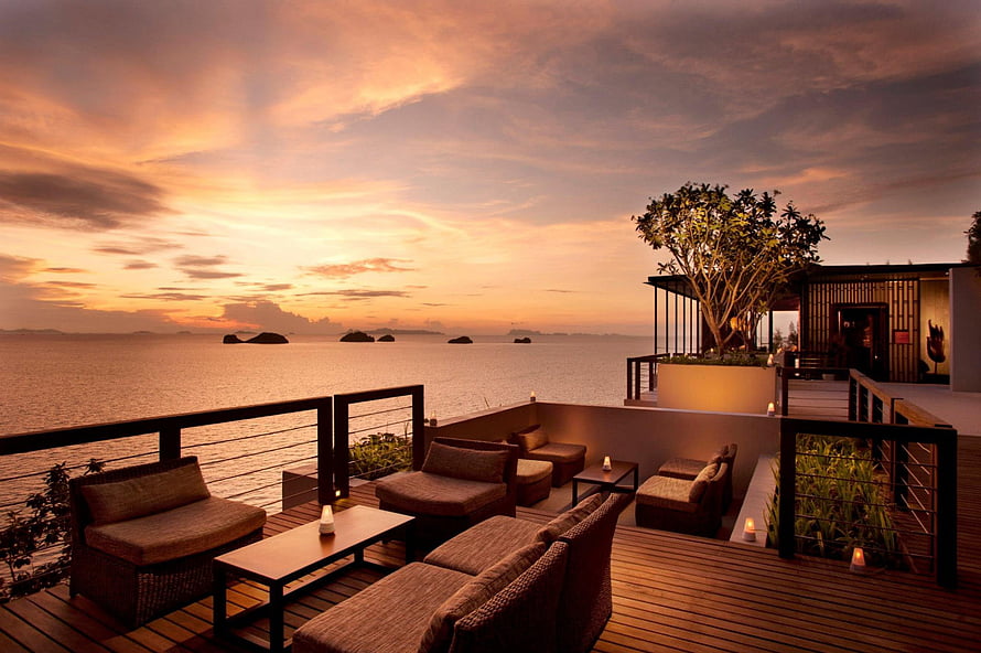Luxury Oceanfront Resort Deck at Dusk with Wicker Seating and Tropical Island View HD wallpaper