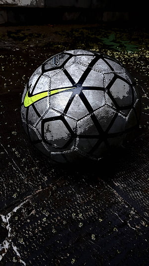 Worn Nike Football on Wet Ground with Neon Swoosh in Moody Low Light HD phone wallpaper